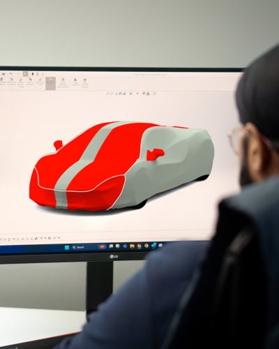 A picture of a computer screen and 3D designer working on some colour schemes for a Mclaren Indoor Plus car cover.