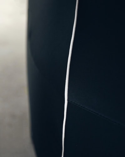 A close up of white piping on a black Indoor Pro Car Cover.