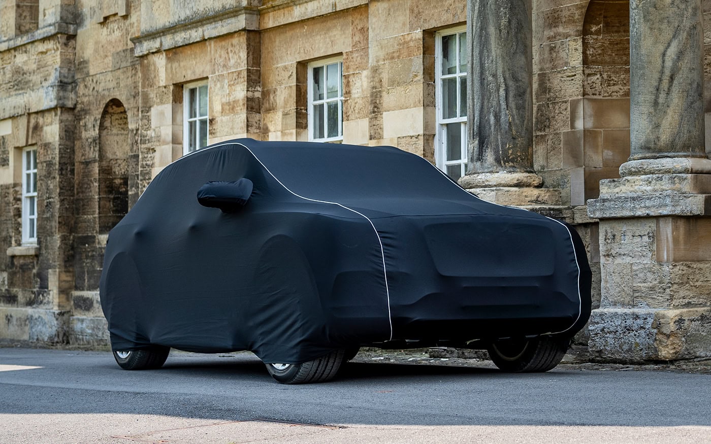 A Bentley with a tailored fitting infoor cover in black with white piping.