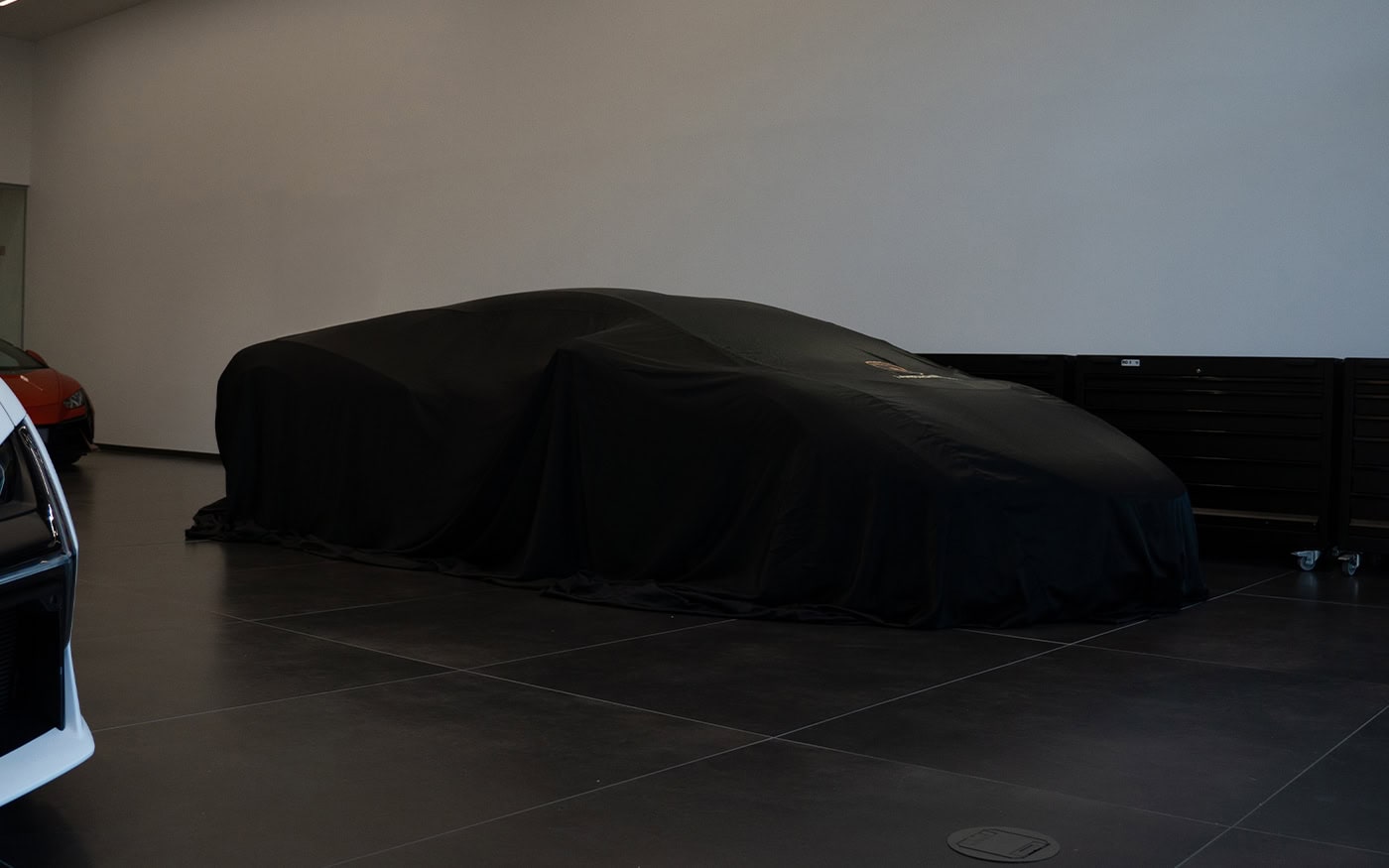 A Lamborghini in a showroom with a black silk style reveal on it.