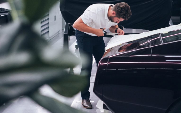 A picture of one of our designers tailoring a cloth pattern to create a car cover.
