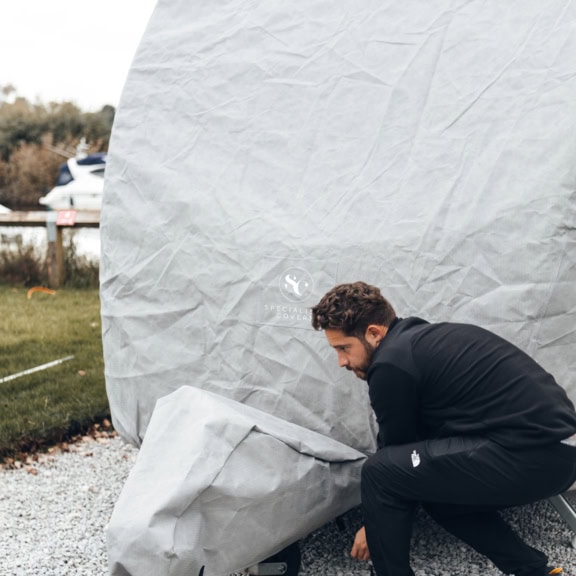 A picture of someone putting on an A-Frame Cover for a Caravan Roof Cover.