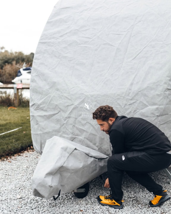 A picture of someone putting on an A-Frame Cover for a Caravan Roof Cover.