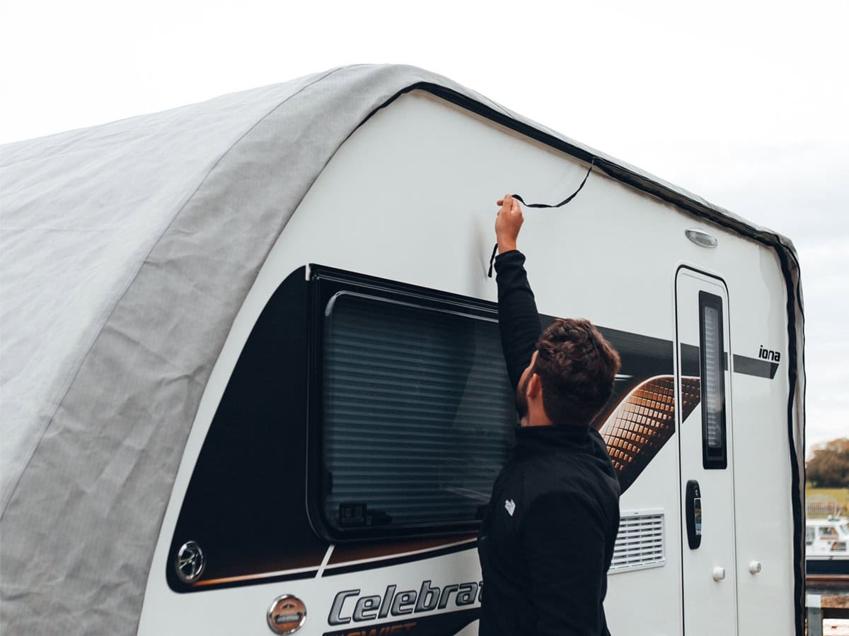 A picture of someone pulling the zip to fit the Caravan Roof Cover.