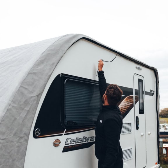A picture of someone pulling the zip to fit the Caravan Roof Cover.